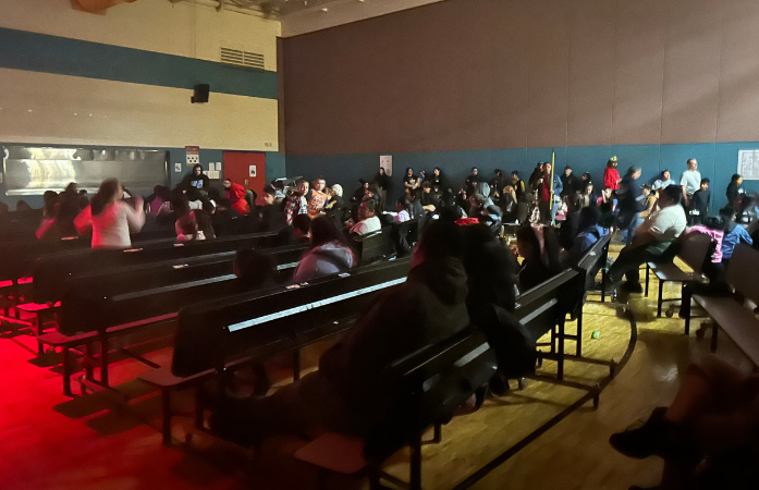 families sitting in the cafeteria watching a movie 
